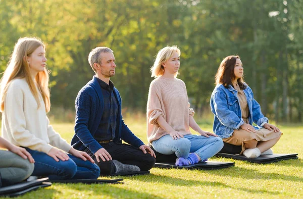 Un grupo de jóvenes meditan al aire libre en un parque . — Foto de Stock