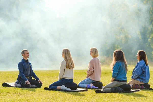Un grupo de jóvenes meditan al aire libre en un parque . — Foto de Stock
