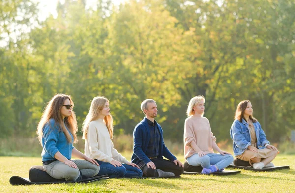 Um grupo de jovens meditar ao ar livre em um parque . — Fotografia de Stock