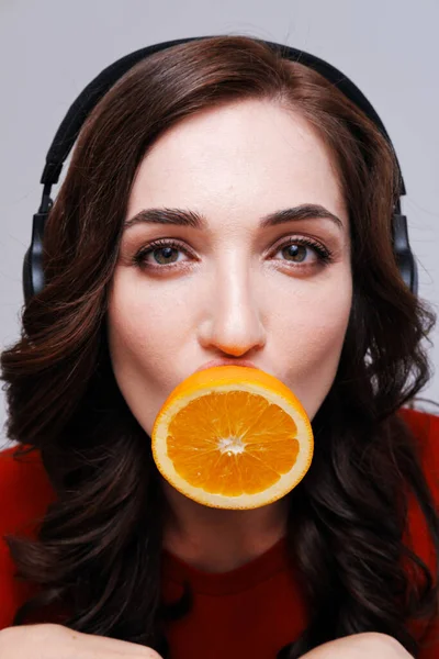 Mujer con auriculares y boca cubierta de naranja — Foto de Stock