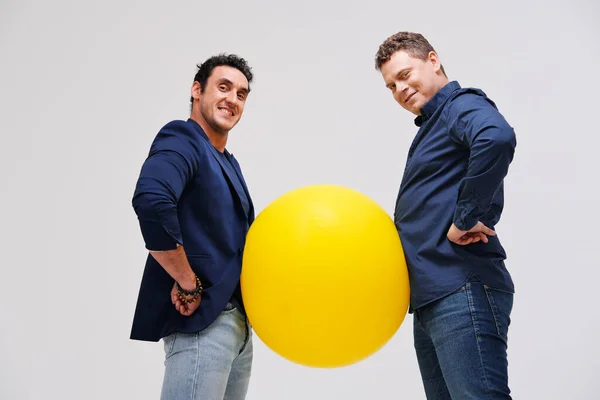 Dos hombres posando con gran bola amarilla — Foto de Stock