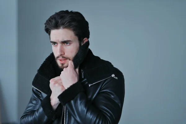 Um grande retrato de um jovem elegante com barba e cabelo escuro em uma jaqueta de couro preto — Fotografia de Stock