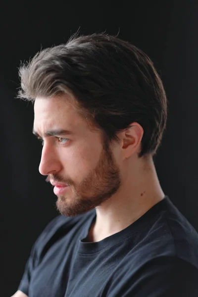 Retrato de close-up de um jovem homem elegante com barba e cabelo escuro em uma camiseta preta — Fotografia de Stock
