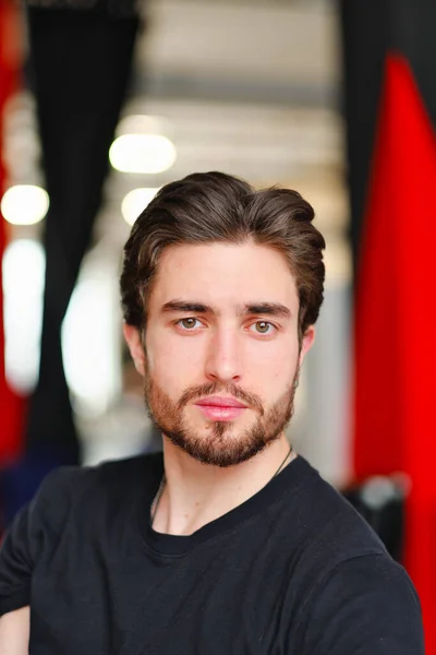 Retrato de close-up de um jovem homem elegante com barba e cabelo escuro em uma camiseta preta — Fotografia de Stock