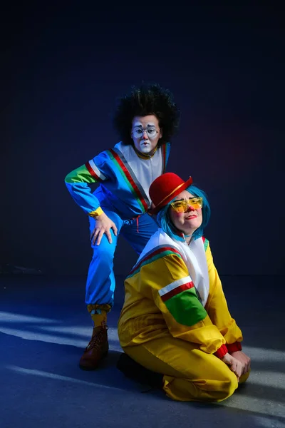 Dois palhaços um homem e uma mulher com maquiagem em trajes coloridos brilhantes no estilo dos anos 80 . — Fotografia de Stock