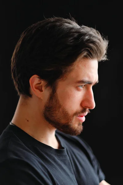 Close-up portrait of a young stylish man with a beard and dark hair in a black T-shirt — Stock Photo, Image