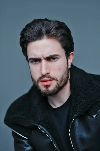 Большой портрет стильного молодого человека с бородой и темными волосами в черной кожаной куртке — стоковое фото