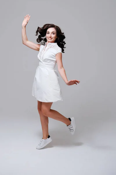 Młoda kobieta w białej sukience i tenisówki skoki — Zdjęcie stockowe