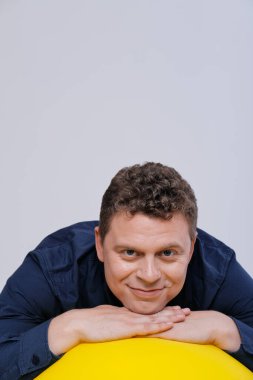 Büyük sarı topla poz veren adamın stüdyo portresi.