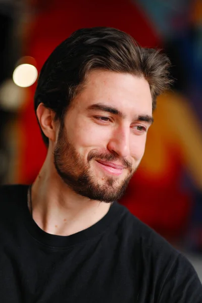 Retrato de close-up de um jovem homem elegante com barba e cabelo escuro em uma camiseta preta — Fotografia de Stock