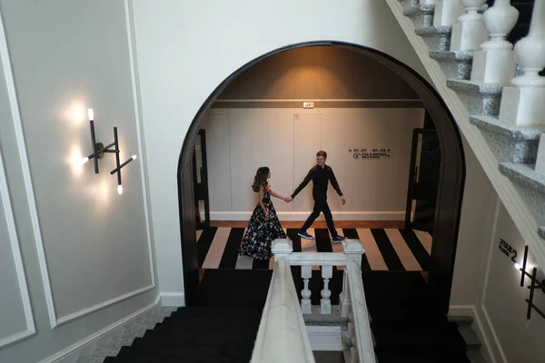 Jeune beau couple une fille et un gars sont debout ou assis sur un escalier blanc à l'intérieur d'un grand beau bâtiment . — Photo