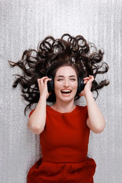 lying woman with headphones and scattered hair