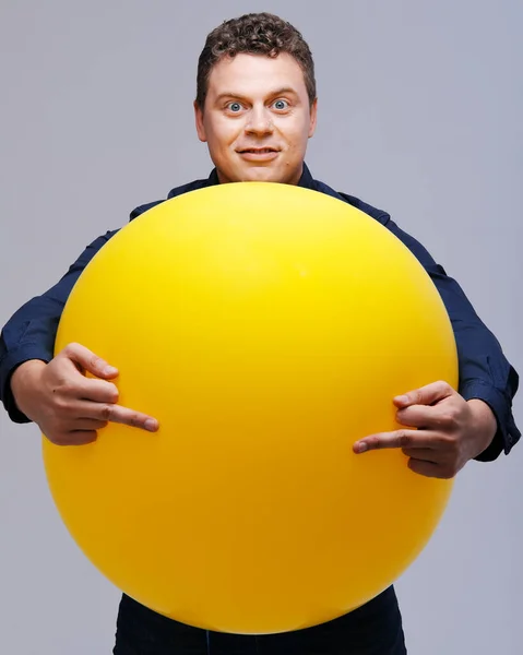 Estúdio retrato de homem posando com grande bola amarela — Fotografia de Stock
