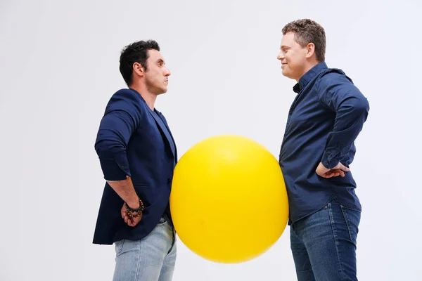 Dos hombres posando con gran bola amarilla — Foto de Stock