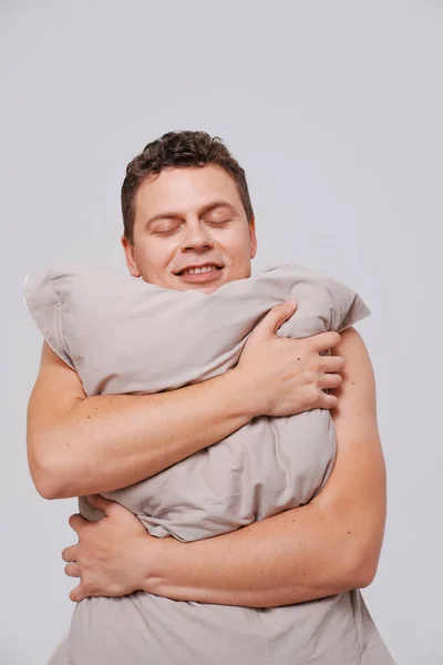 Retrato de estudio del hombre somnoliento sosteniendo almohadas —  Fotos de Stock
