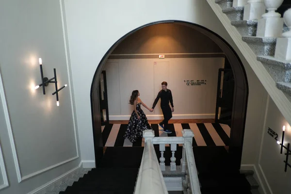 Jeune beau couple une fille et un gars sont debout ou assis sur un escalier blanc à l'intérieur d'un grand beau bâtiment . — Photo