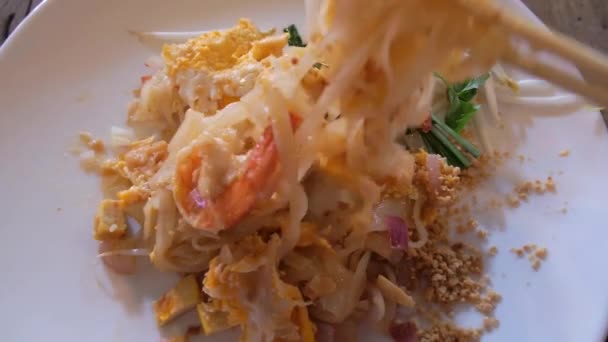 外国游客第一次尝到用虾仁做的亚洲菜 Pad Thai Noodles 用筷子捏盘子里的配料 泰国真正的街头食品 — 图库视频影像