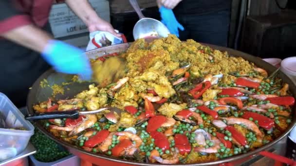 シェフは ムール貝 赤唐辛子を大きな鍋で伝統的なスペインのパエリアを調理し 地元のストリートフード市場で販売するために提供しています — ストック動画