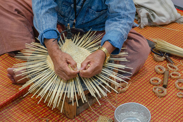 Handmade handcraft wicker rattan and bamboo traditional Thai wooden hat weaving process by artisan craftsman elderly