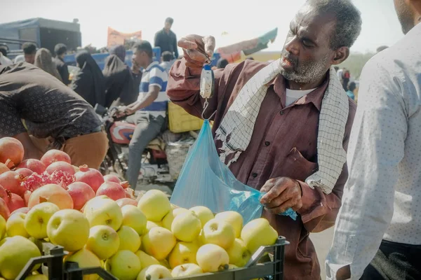 Hormozgan Eyaleti, İran. 27 Ekim 2016: Yerel İranlı sokak meyve satıcısı, perşembe günü Minab 'taki küçük işletmesinde el yapımı asma tartısı kullanarak mal satıyor.