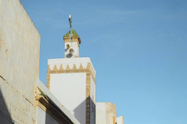 Müslüman beyaz minare kulesi, mavi gökyüzü arka planına karşı yerel camide namaz kılmak için.