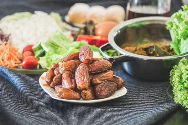 Müslüman aile evindeki yemek masasında iftar ve sahoor yemeği sırasında oruç tutarken organik hurma ağaçları. Ramazan ayı helal yiyecekler, Ramazan kareem ve Kurban Bayramı konsepti