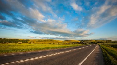 Rusya 'daki bir orman ve tarlalardan geçen boş uzun asfalt bir yol. Gün batımında yol ufkun ötesinde kaybolur..