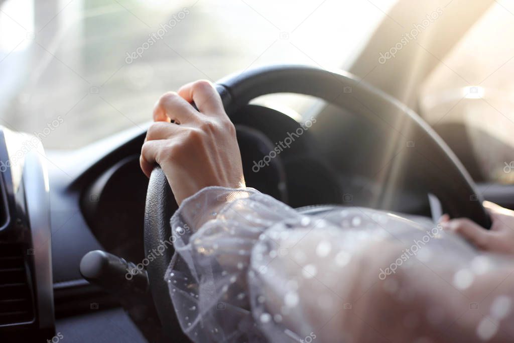 Close-up of hands on steering wheel while driving a car