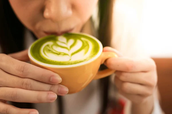 Close up a  beautiful woman with Cup of Matcha green tea latte in cafe