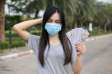 Yüz koruması takan Asyalı kadın, Virüs maskesi para ve kredi kartı problemi, Coronavirus sırasında ekonomik kriz, Covid-19 pandemisi