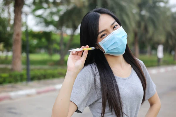 Asian woman  wearing face protection Holding a thermometer Temperature measurement,Virus mask,Healthcare and sickness prevention from coronavirus, Covid19,Selective of focus.