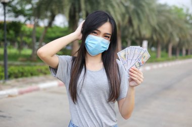 Yüz koruması takan Asyalı kadın, Virüs maskesi para ve kredi kartı problemi, Coronavirus sırasında ekonomik kriz, Covid-19 pandemisi