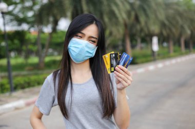 Yüz koruması takan Asyalı kadın, Virüs maskesi para ve kredi kartı problemi, Coronavirus sırasında ekonomik kriz, Covid-19 pandemisi