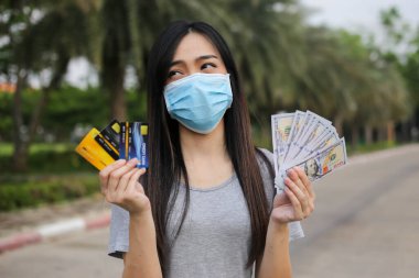 Yüz koruması takan Asyalı kadın, Virüs maskesi para ve kredi kartı problemi, Coronavirus sırasında ekonomik kriz, Covid-19 pandemisi