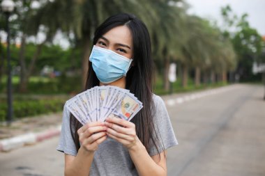 Yüz koruması takan Asyalı kadın, Virüs maskesi para ve kredi kartı problemi, Coronavirus sırasında ekonomik kriz, Covid-19 pandemisi