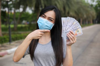 Yüz koruması takan Asyalı kadın, Virüs maskesi para ve kredi kartı problemi, Coronavirus sırasında ekonomik kriz, Covid-19 pandemisi