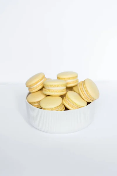Macaron amarillo en un plato blanco sobre un fondo blanco aislado —  Fotos de Stock
