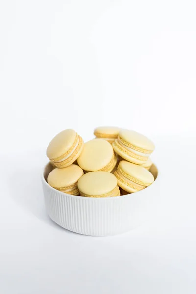 Macaron amarillo en un plato blanco sobre un fondo blanco aislado —  Fotos de Stock