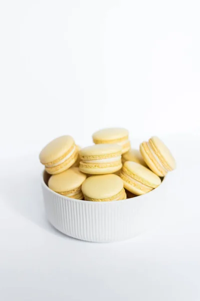 Macaron giallo in una lastra bianca su uno sfondo bianco isolato — Foto Stock