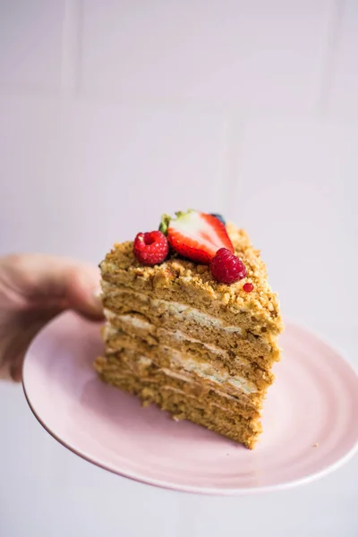 Leckeres Stück Kuchen auf einem Teller in der Hand — Stockfoto