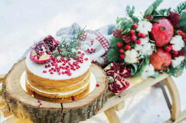 Handmade brown biscuit cake decorated with garnet with cream on the sled 