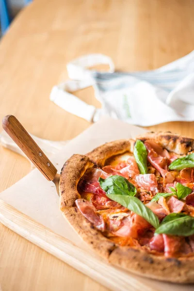 Вкусная пицца стоит на столе, пицца с красным соусом, панчетта и базилик, итальянская кухня, пиццерия — стоковое фото