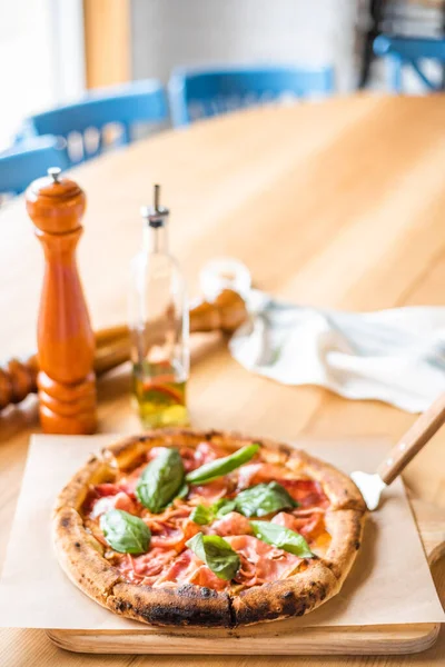 Delicious pizza stands on the table, pizza with red sauce, pancetta and basil, Italian cuisine, pizzeria — 图库照片