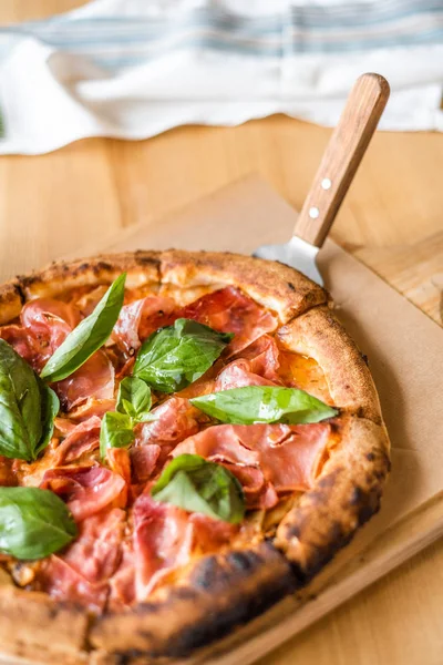 Вкусная пицца стоит на столе, пицца с красным соусом, панчетта и базилик, итальянская кухня, пиццерия — стоковое фото