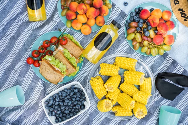 Summertime picnic setting on the grass with open picnic basket, fruit, salad and cherry pie — Stock Photo, Image