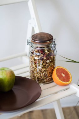 Mutfaktaki beyaz masada cam kavanozda ev yapımı sağlıklı granola.