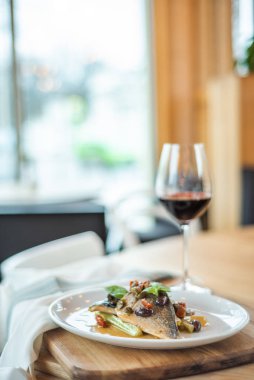 Izgara balık beyaz plaka ve ayaklı büyük kadehler.