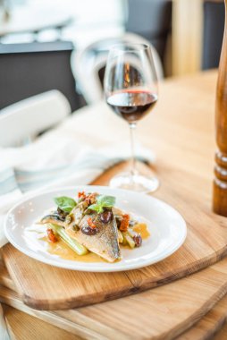 Izgara balık beyaz plaka ve ayaklı büyük kadehler.