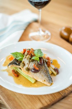 Izgara balık beyaz plaka ve ayaklı büyük kadehler.