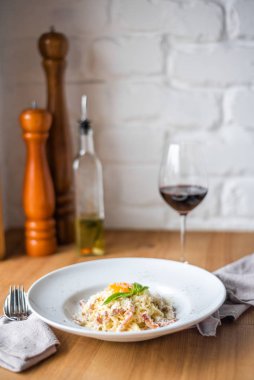 Pancetta 'lı spagetti carbonara, ahşap masada beyaz kasede yumurta ve peynir.